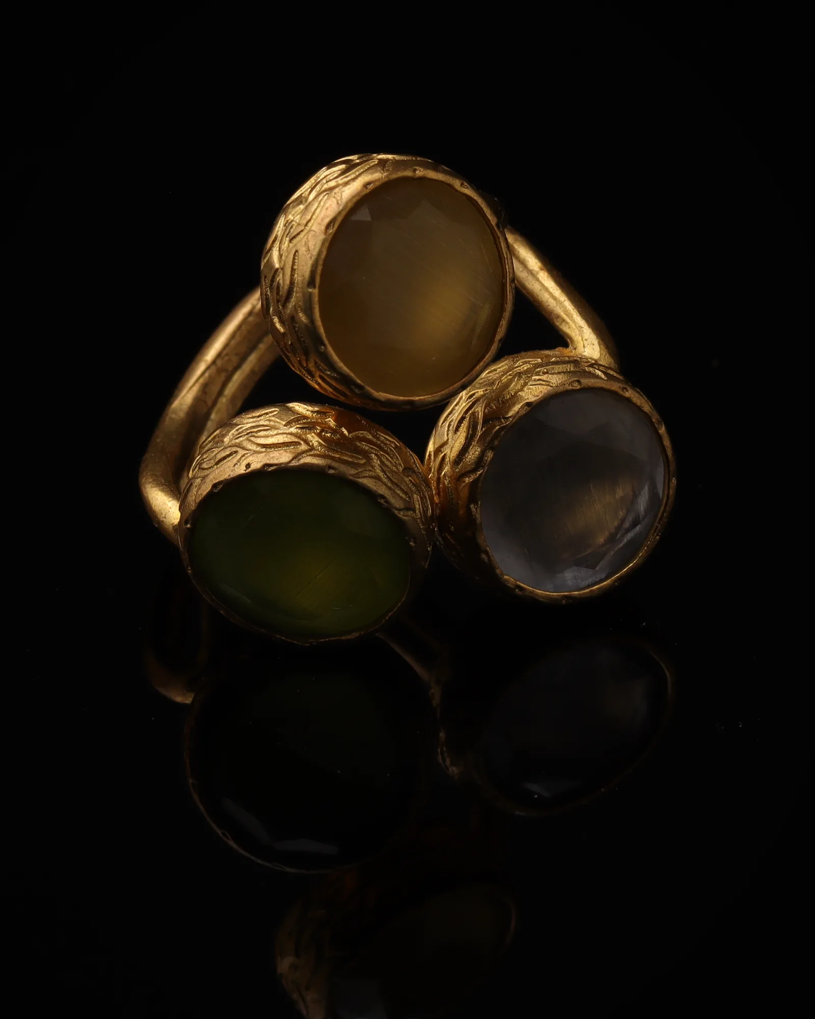Butterscotch & Thyme - a gold-plated ring with three yellow and olive green cat eye stones, on black