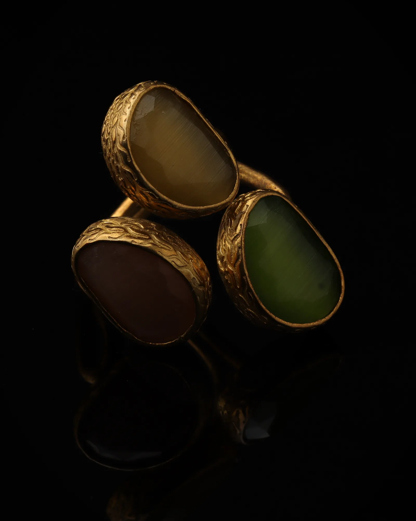 Willow & Mauve - a gold-plated ring with three green and purple cat eye stones, on black