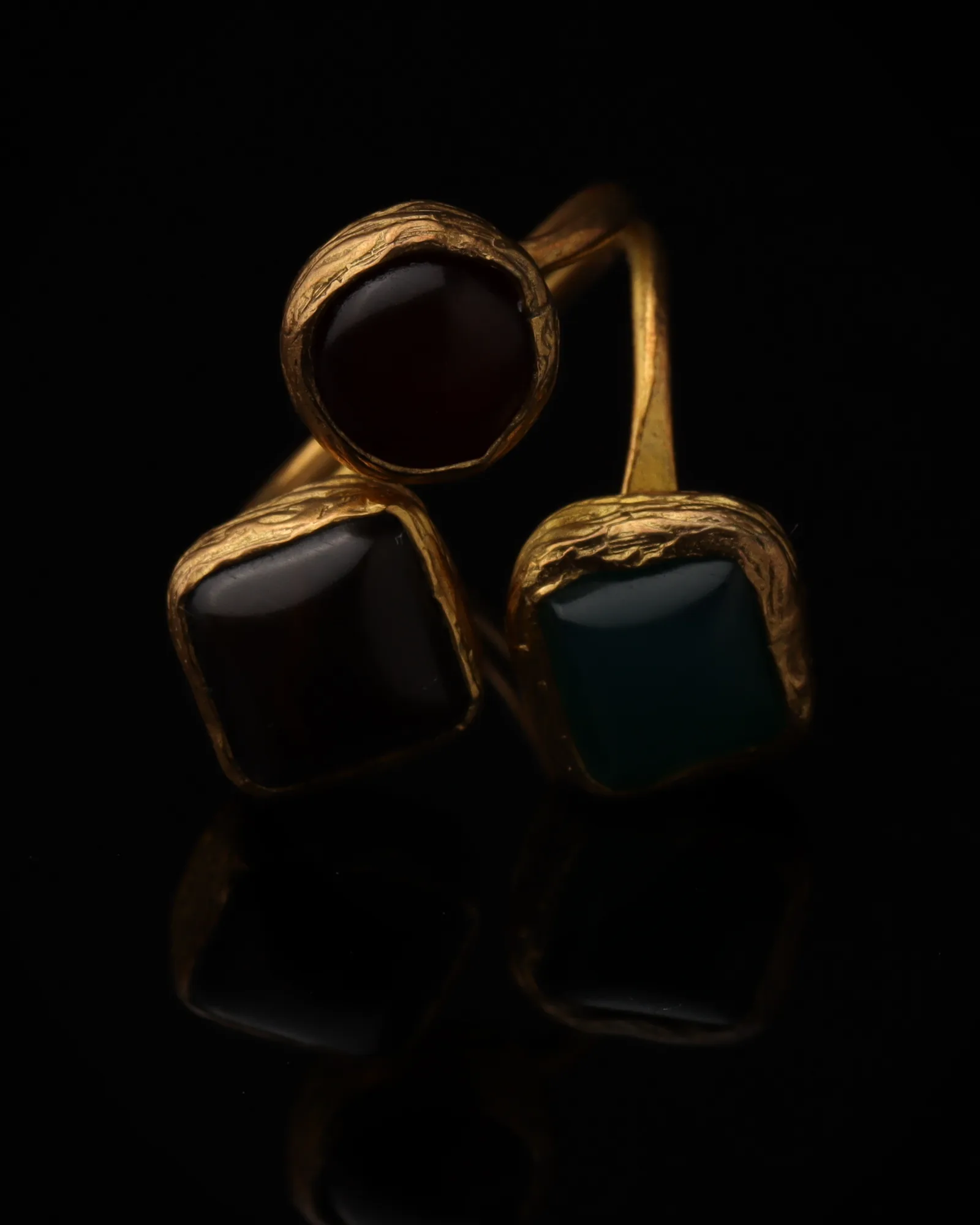 Port & Tide - a gold-plated ring with three red and teal cat eye stones, on black