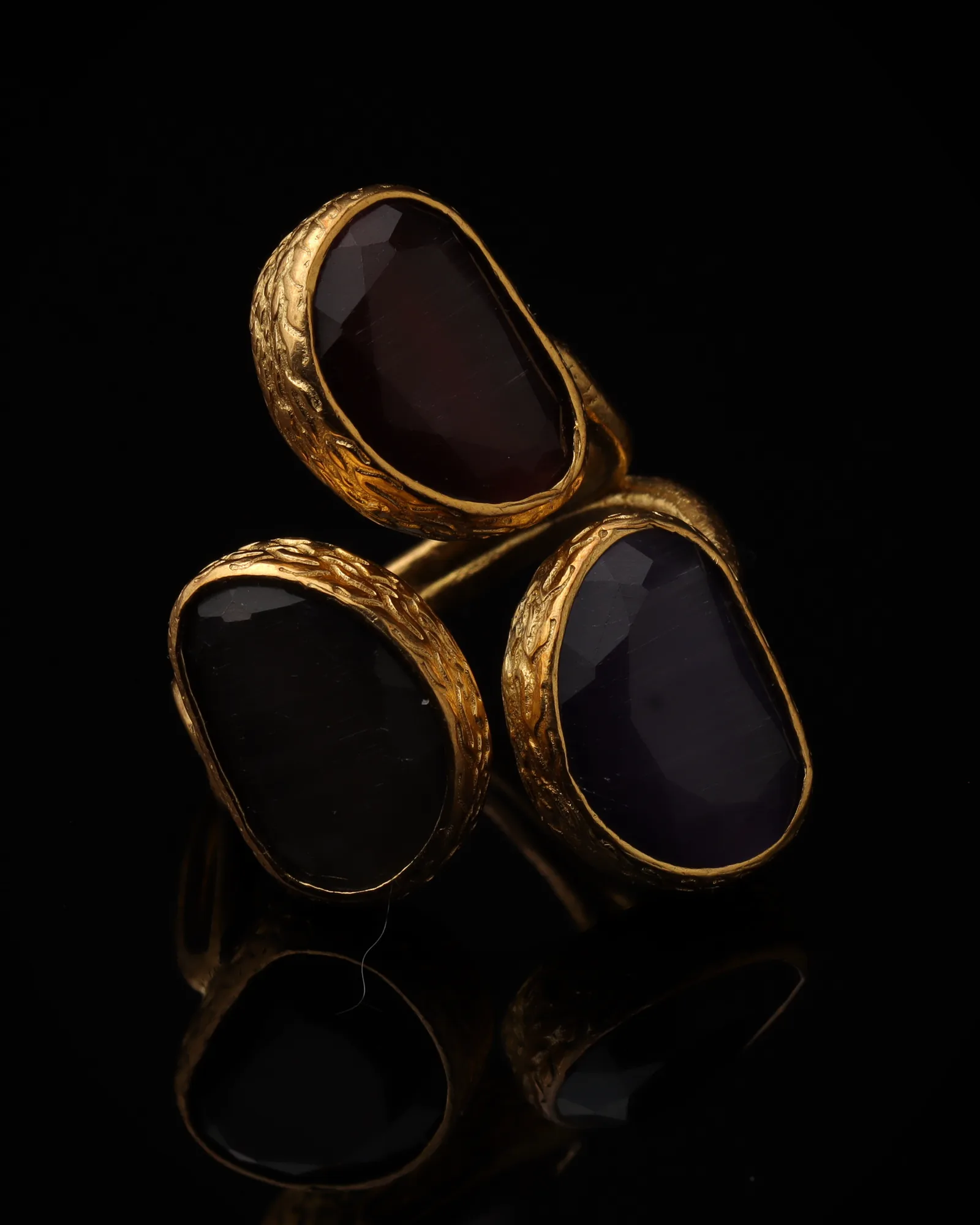 Aubergine & Thistle - a gold-plated ring with three plum and purple cat eye stones, on black