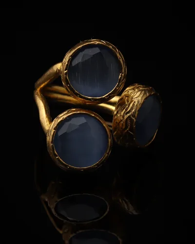 Glacier & Steel - a gold-plated ring with three blue and grey cat eye stones, on black