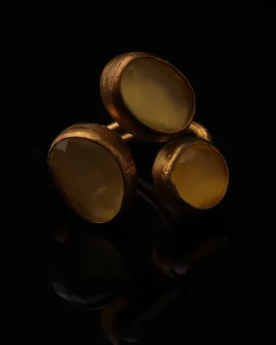 Honeyed Oat - a gold-plated ring with three yellow and cream cat eye stones, on black